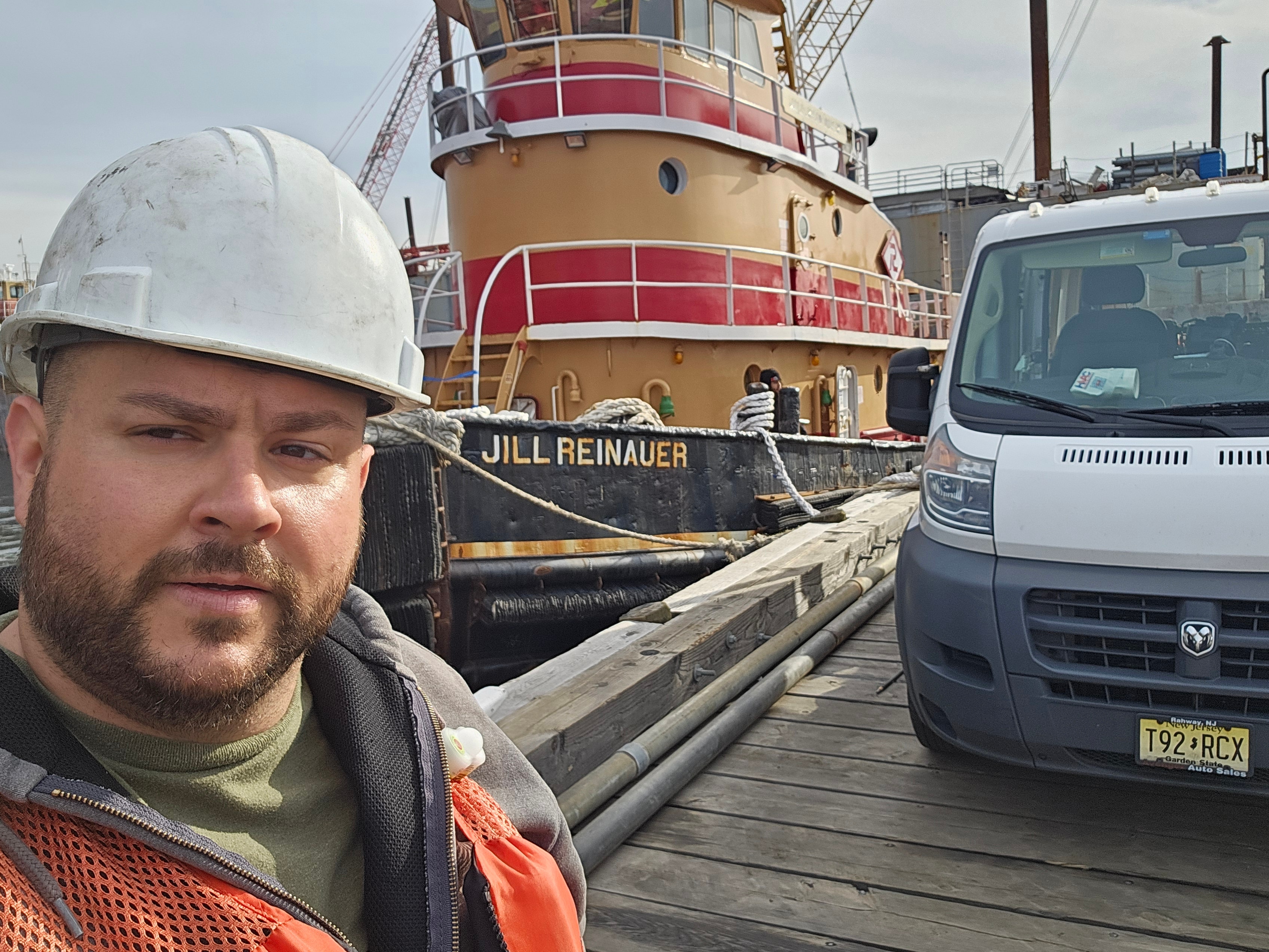 Technician on dock beside tugboat Jill Reinauer — maritime duct cleaning job