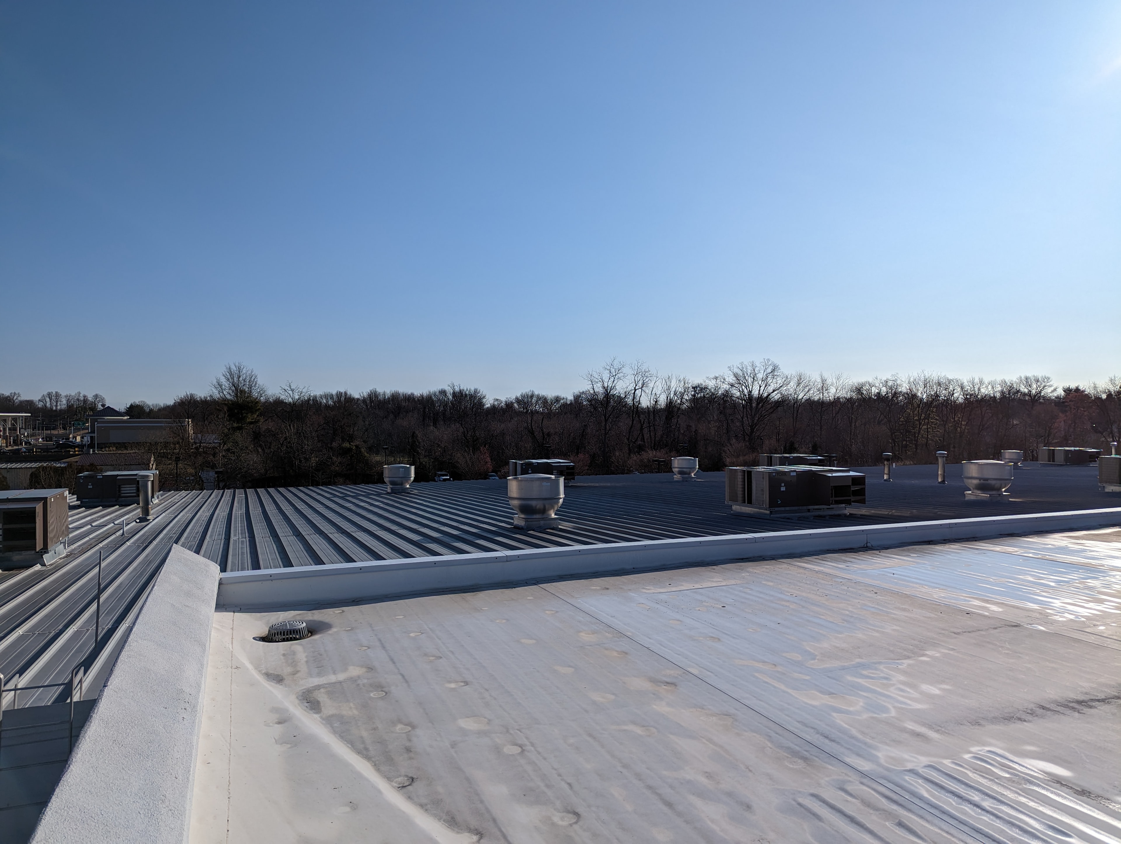 Large commercial rooftop with multiple HVAC units and ventilation stacks