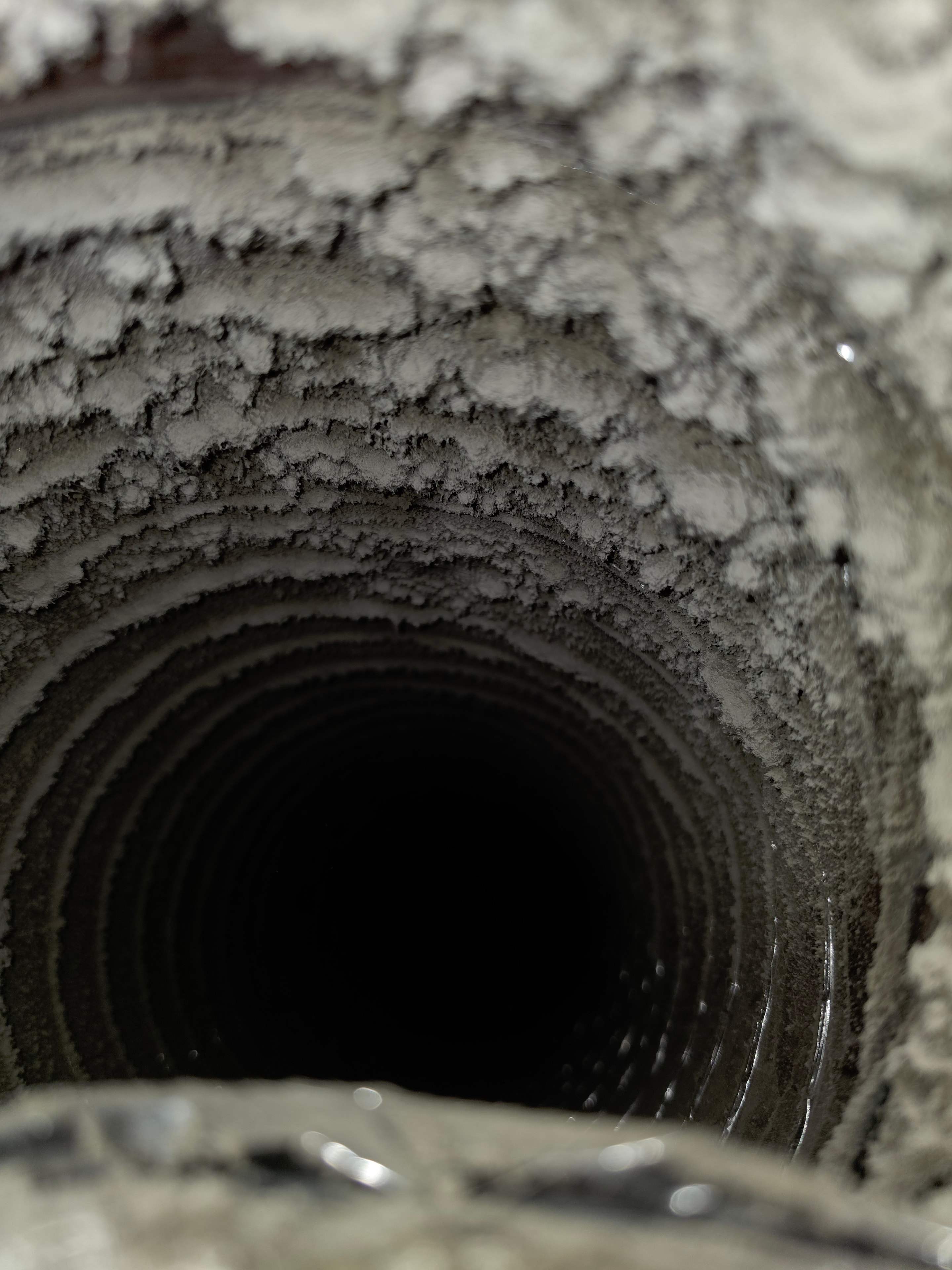 Close-up of duct interior walls coated in thick dust and debris before cleaning