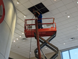 Close up of HVAC Cleaning Specialists cleaning air ducts in a high ceiling of a commercial building