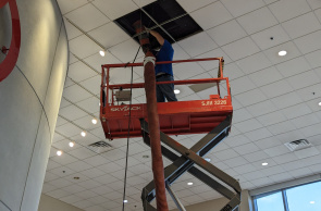 Close up of HVAC Cleaning Specialists cleaning air ducts in a high ceiling of a commercial building